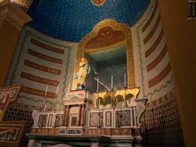...sovrastato dalla statua in cartapesta dell�Immacolata. La sottostante parete curvilinea � caratterizzata dalla sovrapposizione di un basamento con marmi policromi, una fascia con colorati motivi geometrici, un registro superiore con fasce di testi liturgici dorati...